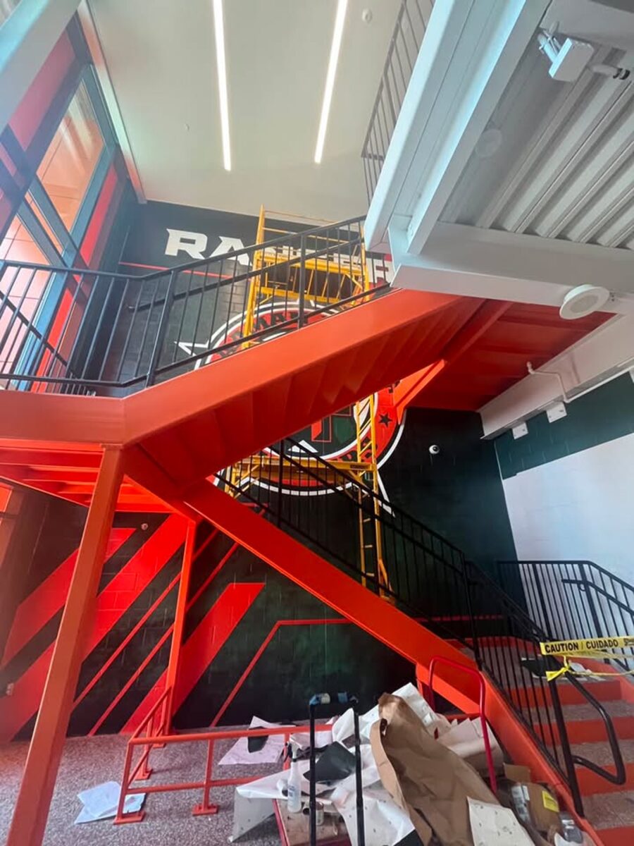Indoor scaffolding set up for high ceiling access on a tall interior stairwell wall