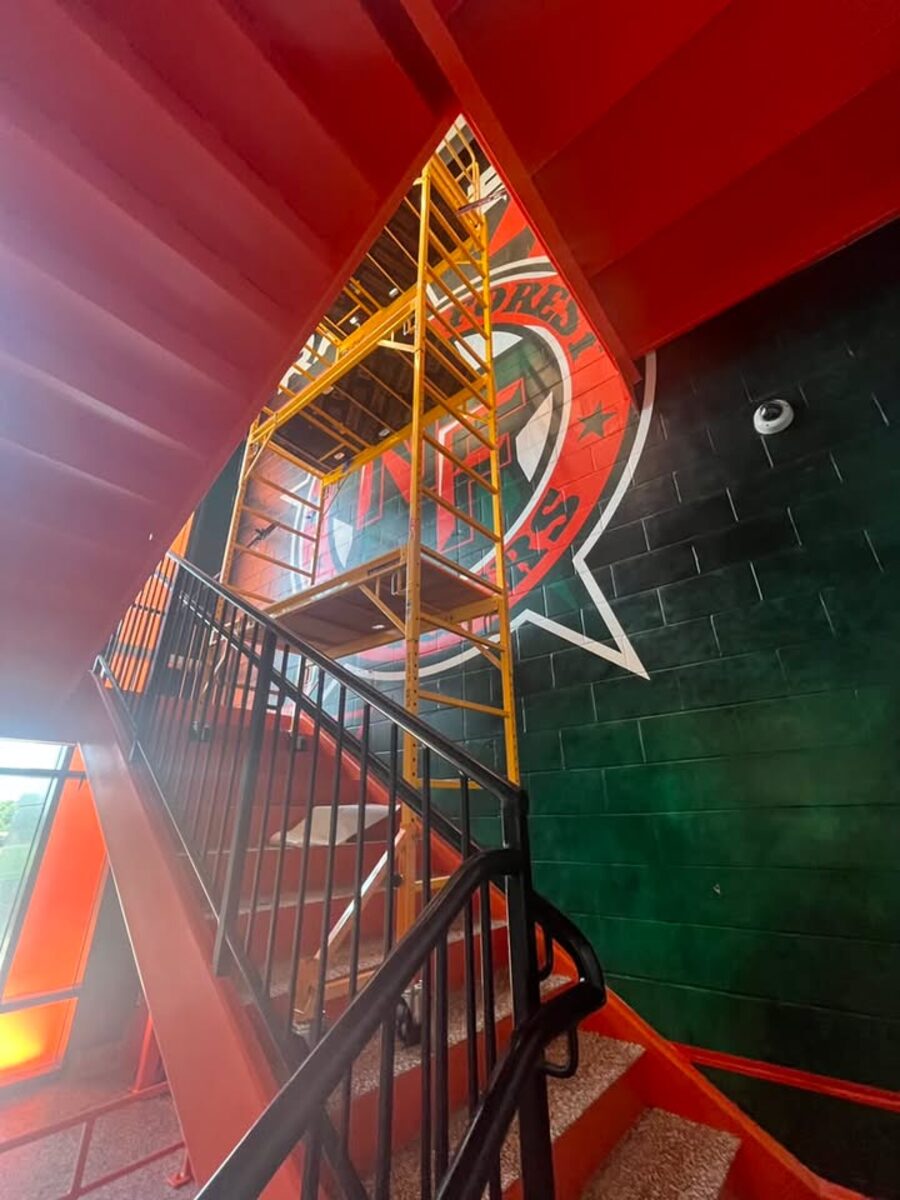 Scaffold tower with locking casters reaching a two-story stairwell ceiling