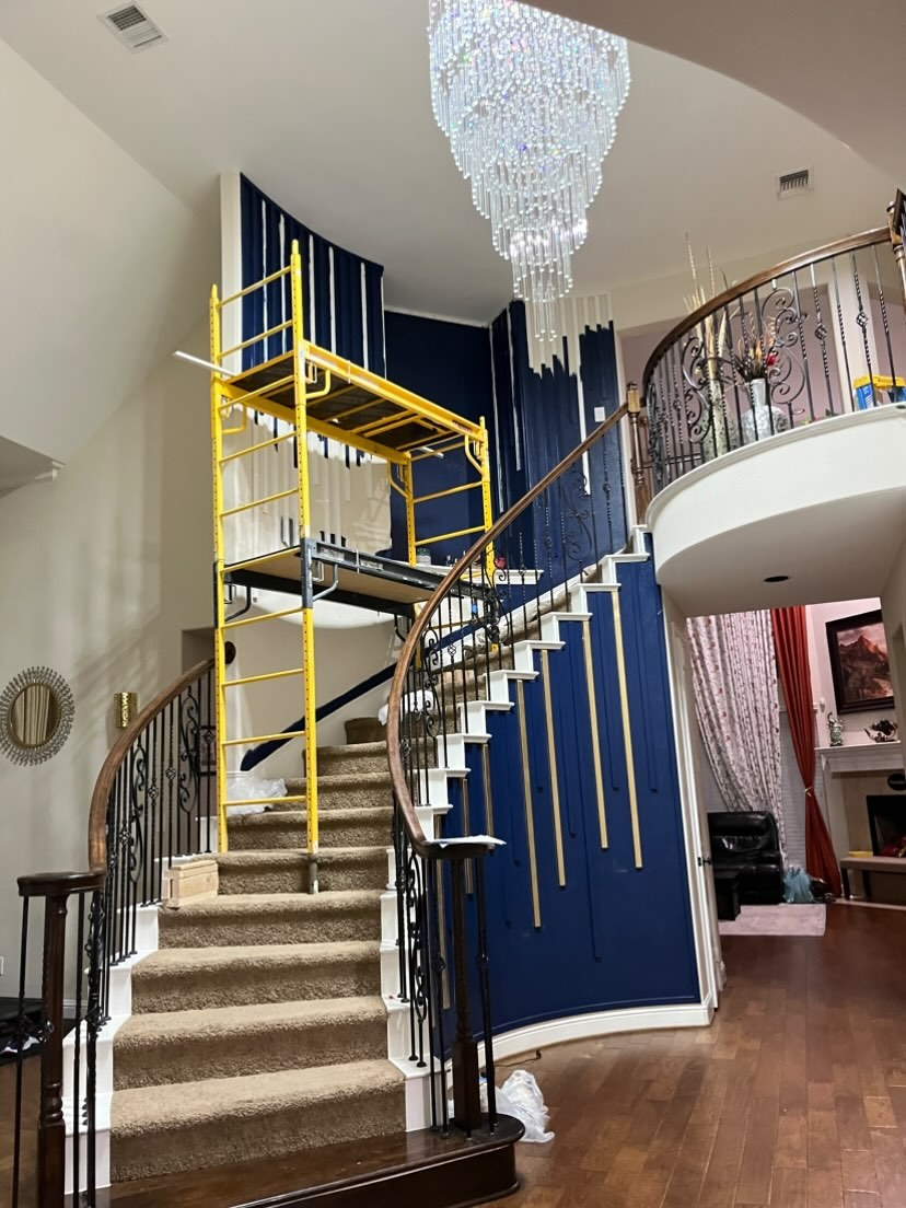 Scaffold tower set up over a curved staircase to safely reach a two-story foyer chandelier in North Dallas