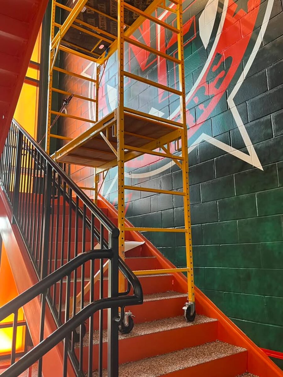 Rolling scaffold tower leveled over a staircase for stairwell wall work in North Dallas