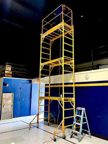 Tall indoor scaffolding setup reaching a gymnasium ceiling